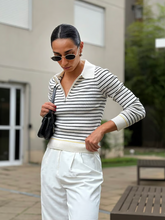 a lady in a black and white stripe sweater with white pants